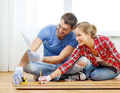 微笑的一对夫妇测量木地板粮食男朋友屋主地板铅笔男人装修地面房子建筑图片