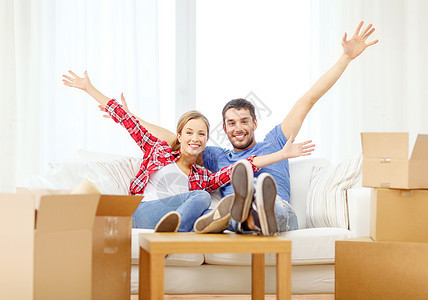 在新家沙发上放松的一对笑着微笑的情侣纸板已婚包装开箱男性盒子幸福房子搬迁投资图片