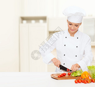 笑着的女厨师切花生菜工作厨房帽子美食管理人员食物木板女性餐厅面包师图片