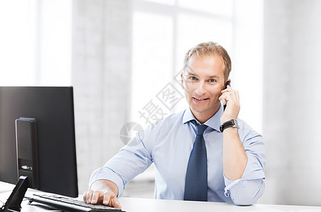 手持智能手机的笑着微笑的商务人士电话企业家工作男人电脑老板工人中年技术办公室图片