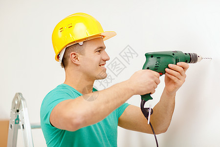 从事电钻的人在墙上挖洞工匠装修建筑穿孔工人力量安全帽领班螺丝刀工具图片