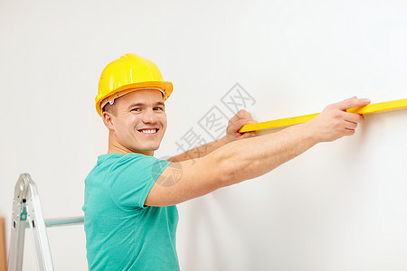 利用精神水平测量人造的笑着男子检查男性安装装修工人仪表改造安全帽工匠成人图片