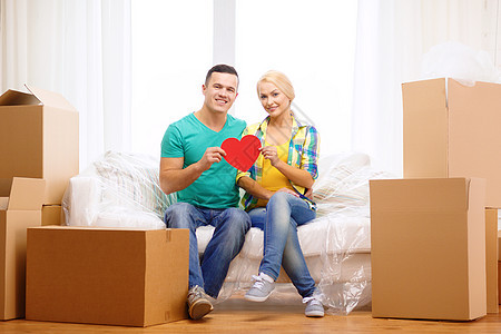 在新家沙发上微笑着红心的情侣教练抵押纸板包装女性房子成人财产开箱公寓图片