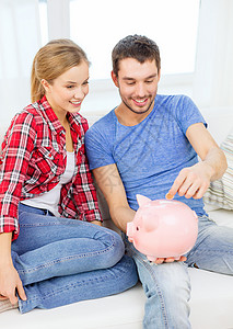 坐在沙发上的一对笑着的夫妇和小猪银行金融收益薪水微笑货币现金财富已婚家庭小猪图片