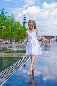 小可爱女孩在阳光明媚的日子里 在露天街道喷泉里走着裙子城市飞溅太阳反射喜悦活动童年微笑街道图片