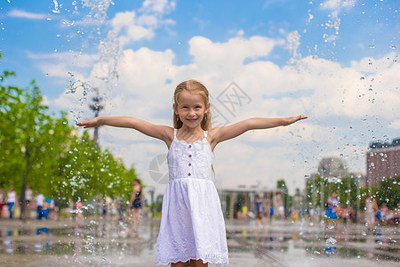 小可爱女孩在阳光明媚的日子里 在露天街道喷泉里走着女性幸福微笑活动反射裙子友谊游戏童年飞溅图片