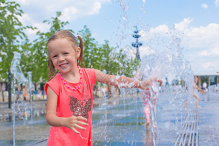小可爱女孩在阳光明媚的日子里 在街头喷泉玩得开心童年孩子乐趣孩子们活动反射城市微笑幸福游戏图片