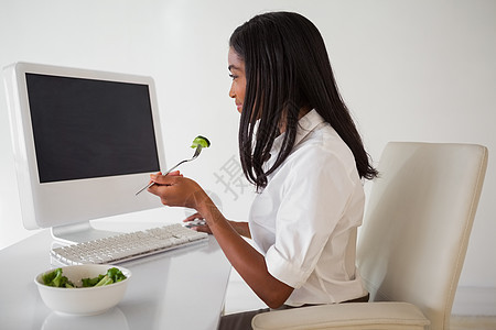 在她桌子上吃沙拉的 临时漂亮商业女商务人士食物女性女士职业时间电脑显示器人士饮食混血屏幕图片
