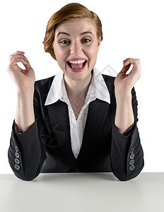 坐在办公桌旁的令人兴奋的红头发女商务人士快乐公司职业商业女士女性微笑商务红发桌子背景图片
