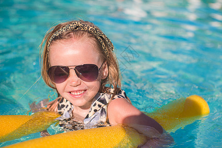 可爱的小女孩在游泳池里享受旅行太阳镜假期晴天太阳蓝色快乐游泳衣牙齿婴儿图片