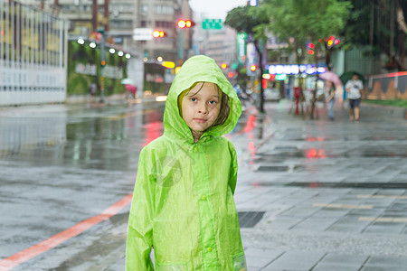 年轻女孩站在雨中 穿着绿色雨衣外套天气雨量女性季节微笑街道眼睛树木倾盆大雨图片