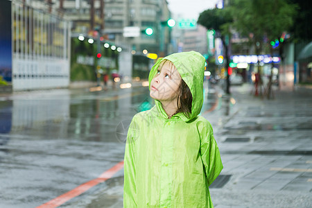 穿着绿色雨衣站在雨中年轻女孩眼睛树木微笑女性乐趣孩子下雨倾盆大雨雨量外套图片