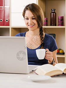 美丽的女人在使用笔记本电脑时微笑图片