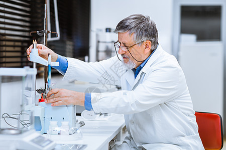 在实验室进行科学研究的高级男性研究员微笑技术生物学化学家技术员烧瓶显微镜男人实验外套图片