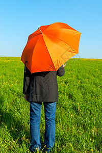 人们在橙色的雨伞下 在田里等待雨水高清图片