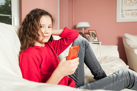 年轻女孩移动电话乐趣互联网卷发孩子学生女性青少年房间教育技术图片