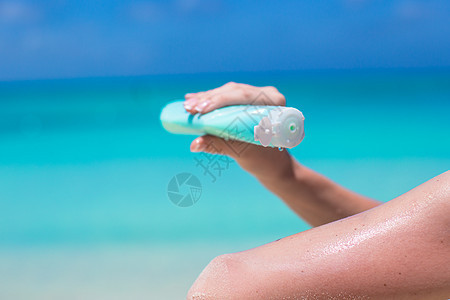 女人用手从防晒霜瓶子上涂防晒霜推杆海滨日光浴假期防晒润肤阳光女性女孩晒黑图片