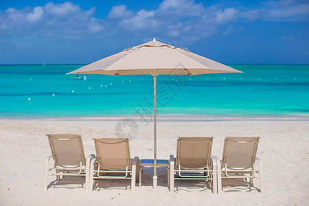 热带海滩的白色雨伞和防晒床晴天蓝色酒店闲暇椅子天堂旅行假期旅游阳伞图片