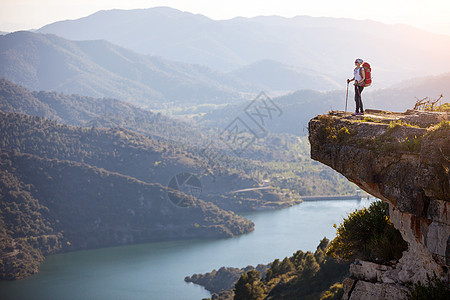 女性登山者站在悬崖上享受风景边缘旅行游客高度远足太阳自由农村活动岩石图片