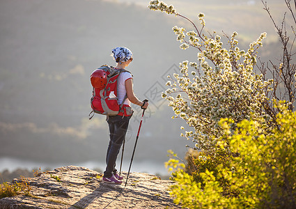 女性登山者站在悬崖上享受风景农村旅行吊带背包高度女士太阳爬坡自由游客图片