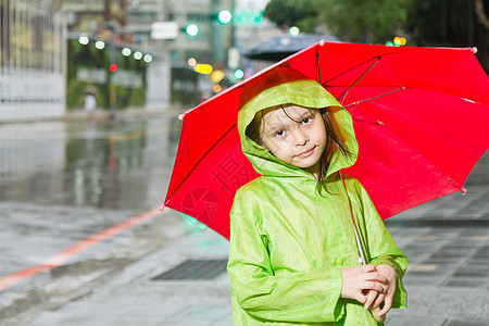 年轻女孩站在雨雨中 穿着雨衣和雨伞天气外套雨量乐趣倾盆大雨眼睛孩子女性下雨微笑图片