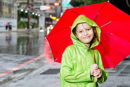 年轻女孩站在雨雨中 穿着雨衣和雨伞雨量倾盆大雨外套孩子微笑街道女性下雨树木眼睛图片