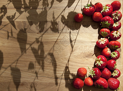 木制桌上的新鲜草莓乡村花园水果甜点收成叶子木板树叶浆果木头图片