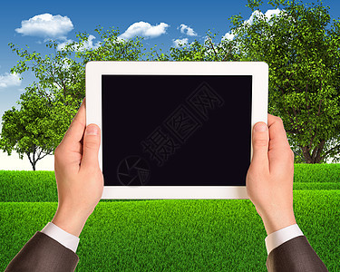 数字平板电脑与草地和树木作为背景放在一起图片