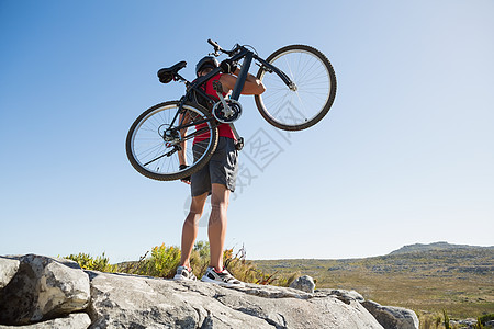 在岩石地形上骑着自行车的合适男子图片