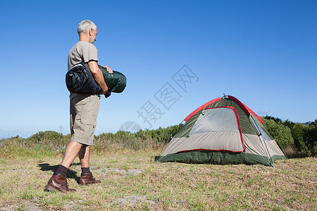快乐的露营者走近他的帐篷 拿着睡袋图片