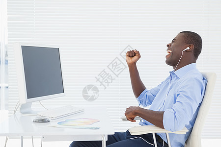 商务人士在工作时听音乐的音乐耳机休闲男人蓝色人士微笑老鼠听力旋转椅电脑显示器图片