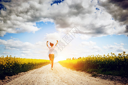 快乐的年轻女子跑来跳去奔向太阳图片