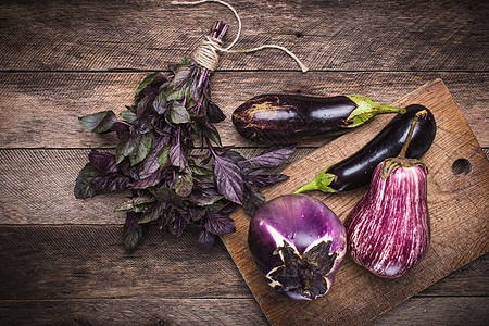 Aubergines和Basil在砍板和木制桌子上植物木板乡村簇绒饮食厨房季节木头食物茄子图片