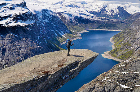 顶部下雪的挪威Trolltunga 的Hiker背景