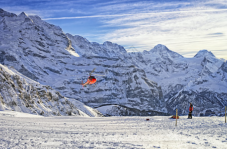 红直升机飞越Jungfrau山塔附近的Swis滑雪胜地图片