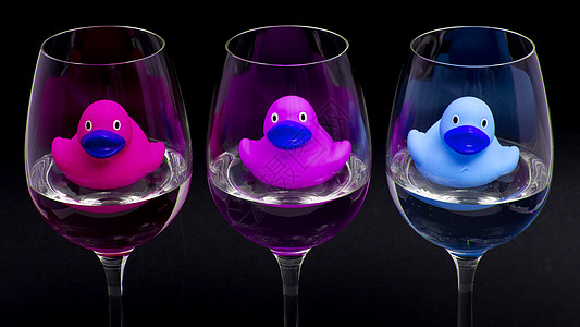 葡萄酒杯中的粉色 紫色和蓝色橡胶鸭玻璃餐厅口渴动物酒吧漂浮浴室浴缸孩子乐趣图片
