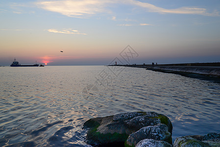 码头和过往船只的日落流动海湾海岸旅游蓝色港口巨石橙子信号岩石图片