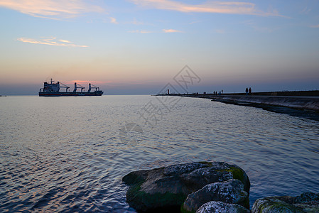 码头和过往船只的日落海湾溪流旅行衬垫港口天空海岸线导航灯塔橙子图片