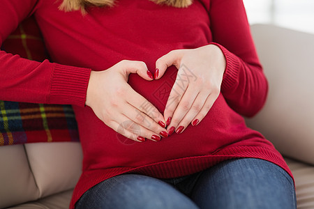 紧贴一个孕妇的近身 在她的肚子上做心脏标志女士住所新生活房子怀孕双手心形家庭微笑女性图片