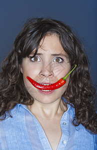 女人嘴里握着辣椒女士胡椒女孩食物黑发嘴唇红色蔬菜情感香料图片