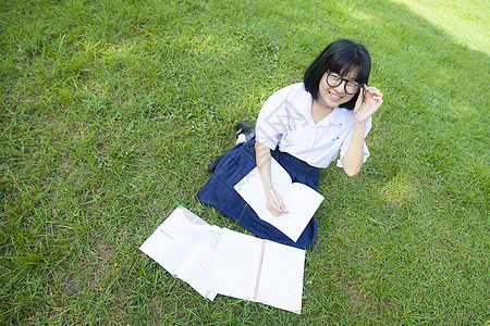 女孩在草坪上读书闲暇学生青年大学女性教育铅笔女士孩子微笑图片