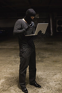使用笔记本电脑窃取身份的黑客手机背景阴影犯罪网络刑事骇客黑色火炬男人图片
