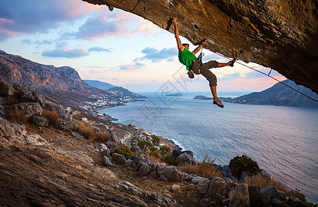 男性登山者攀爬在悬浮的岩石上高度日落运动挑战天空太阳成人绳索悬崖风景图片