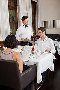 高档菜单餐馆里微笑的年轻夫妇奢华菜单男人订购服务夫妻桌子女性玻璃庆典背景