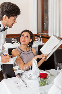高档菜单餐馆里微笑的年轻夫妇桌子庆典服务俱乐部男人奢华款待女性饮料玻璃背景