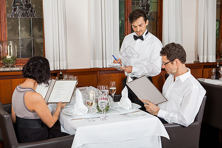 高档菜单餐馆里微笑的年轻夫妇服务员玻璃女士饭厅庆典俱乐部食物服务夜生活午餐背景
