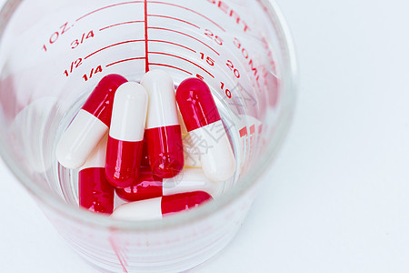 玻璃杯中的白色红色胶囊药剂治愈抗生素愈合疼痛剂量团体收藏疾病宏观图片