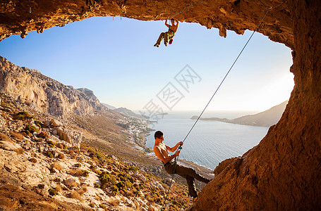 男性攀岩者爬上山洞中的屋顶洞穴伙伴高度活动男人登山者绳索天空悬崖运动图片