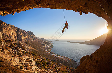 攀岩者悬在绳索上 同时铅攀山太阳海岸岩石高度登山者悬崖男人天空成人运动图片