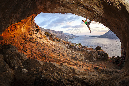 男性攀岩者在山洞的屋顶上攀爬岩石悬崖男人登山者天空日落成人高度活动洞穴图片